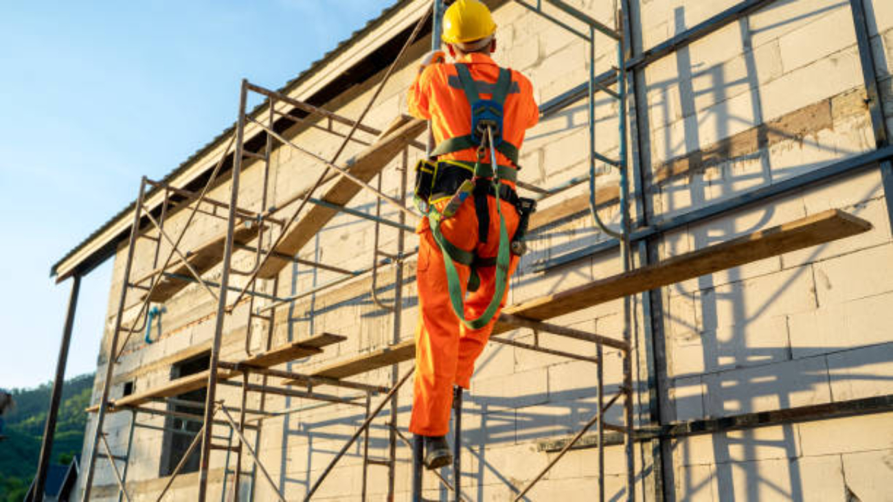 Construction worker wearing safety harness belt during working at high place at construction site.