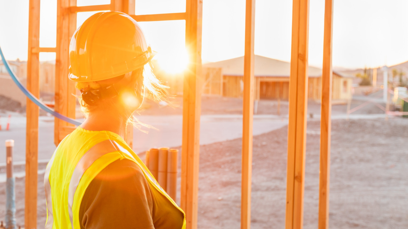 Female Construcion Worker Looking Out From New Home Framing with the sun shining