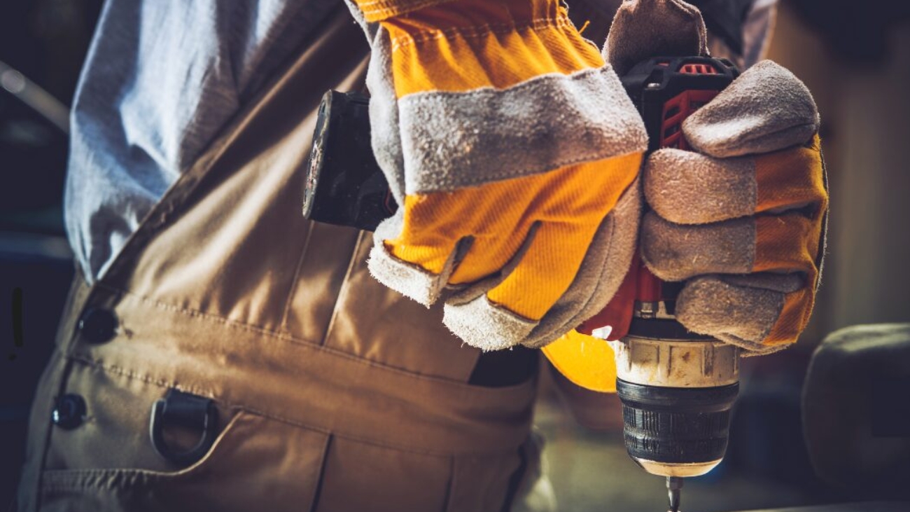 Hand with gloves holding a drill