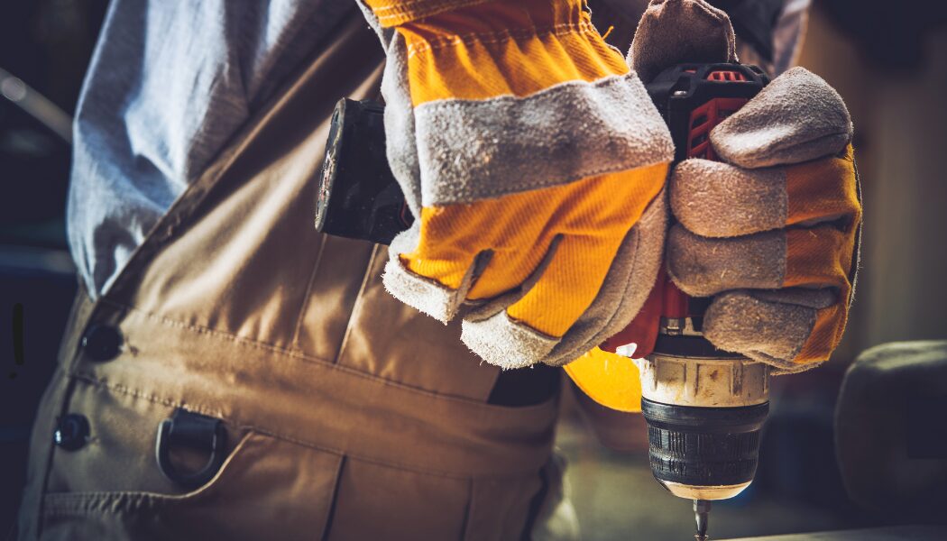 Hand with gloves holding a drill