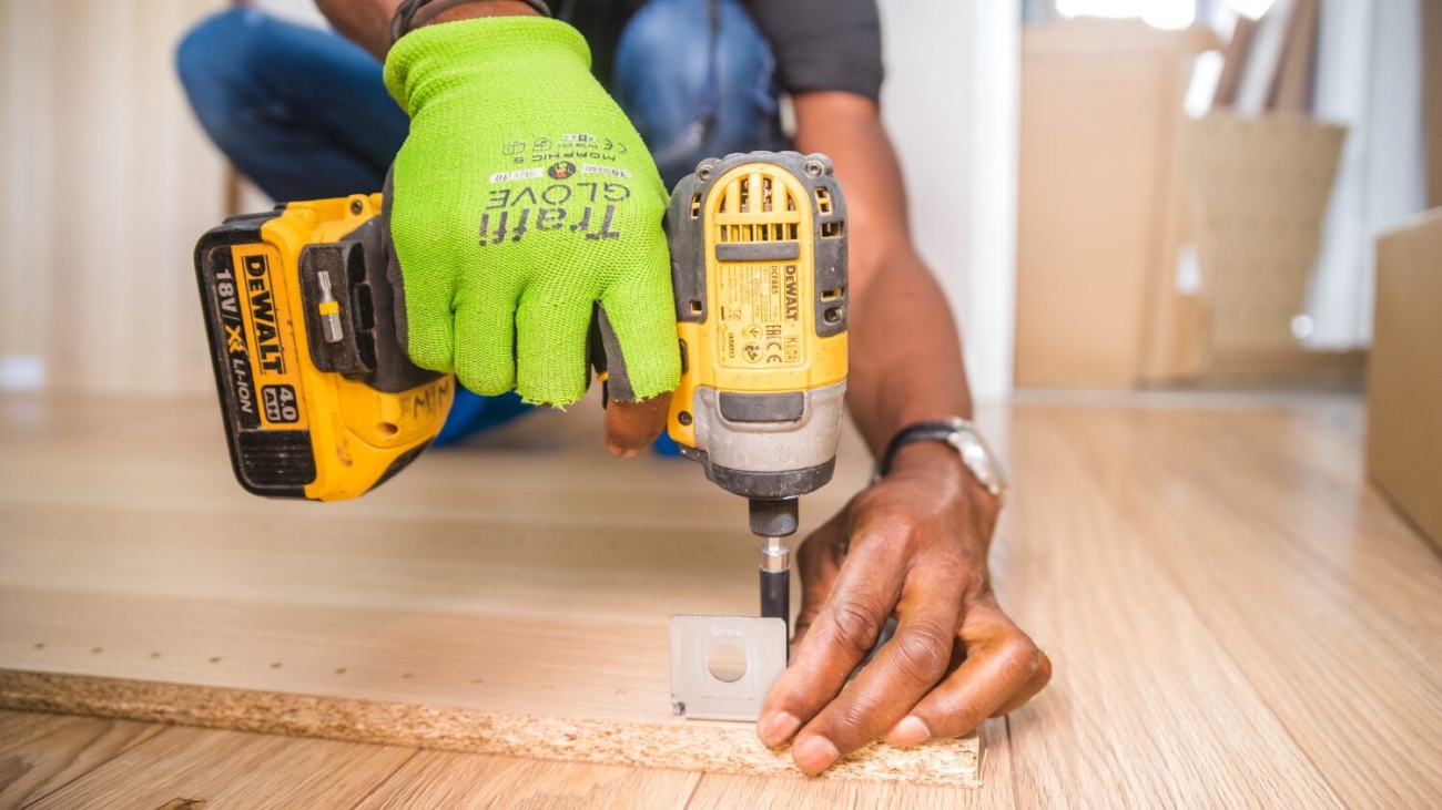 Man wearing green gloves and holding a tool