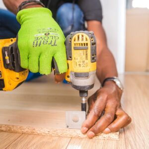 Man wearing green gloves and holding a tool