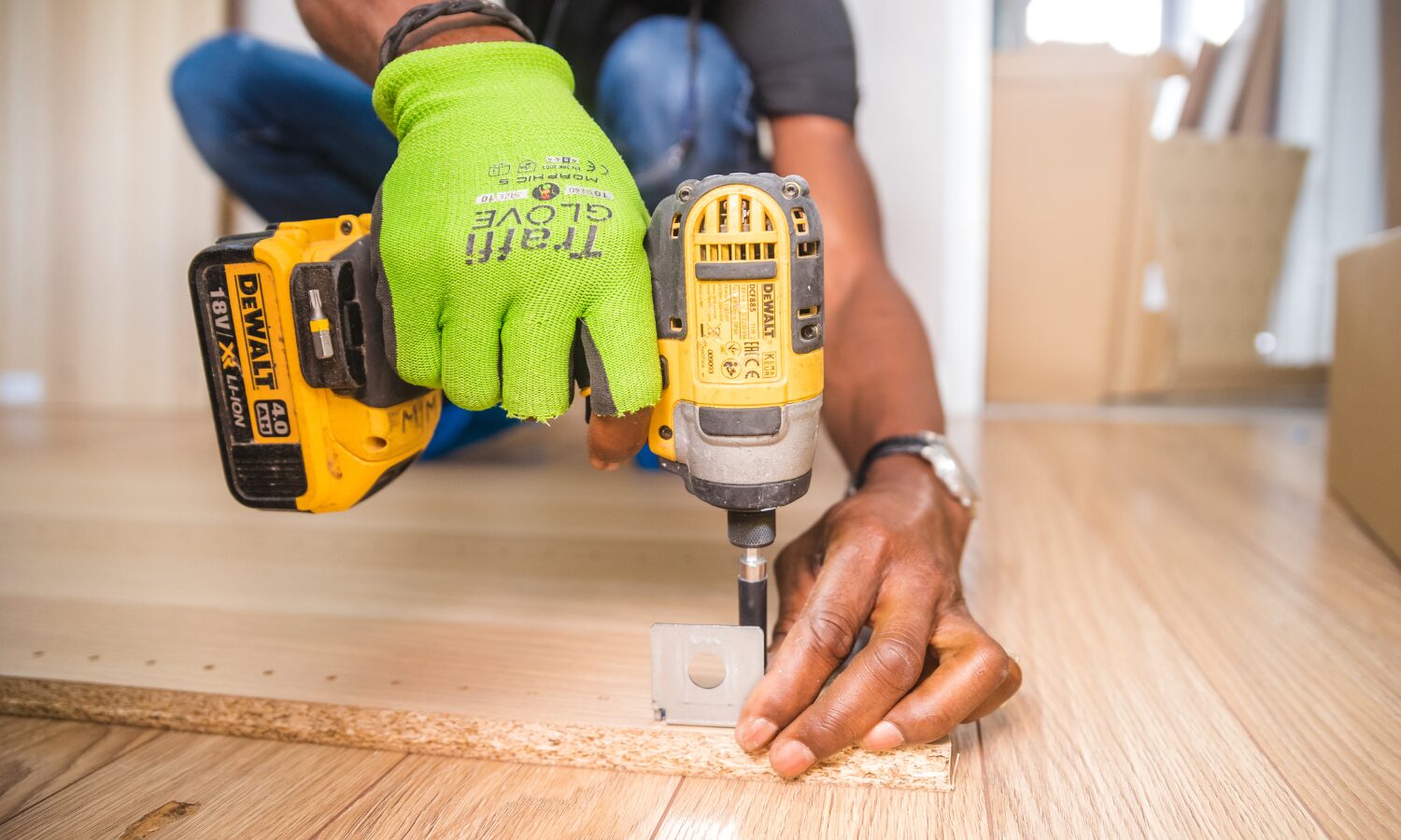 Man wearing green gloves and holding a tool